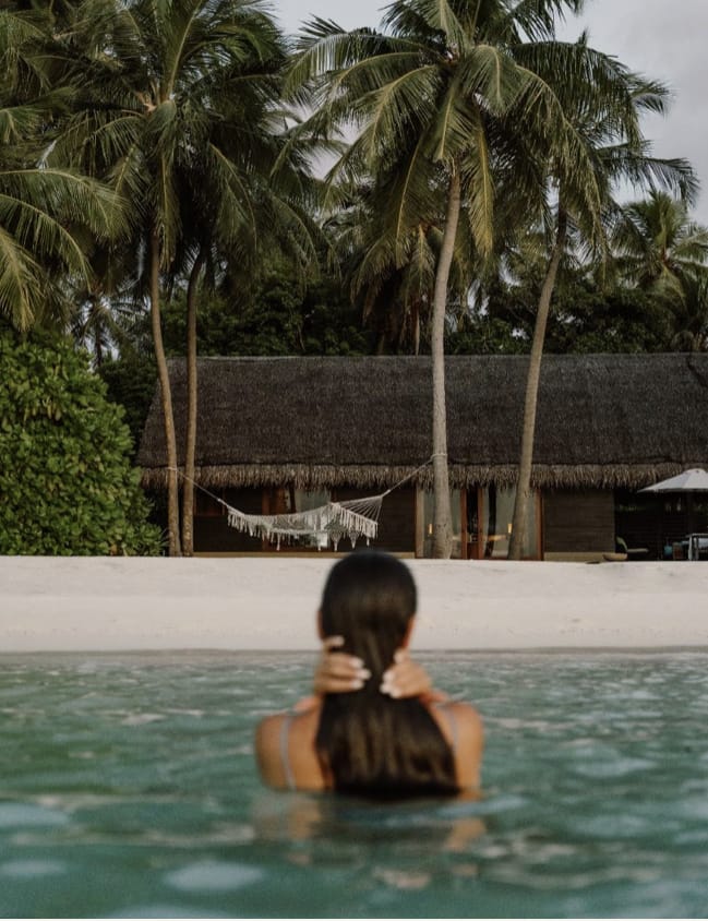 A guest enjoying a quiet pool beneath palms at a private villa